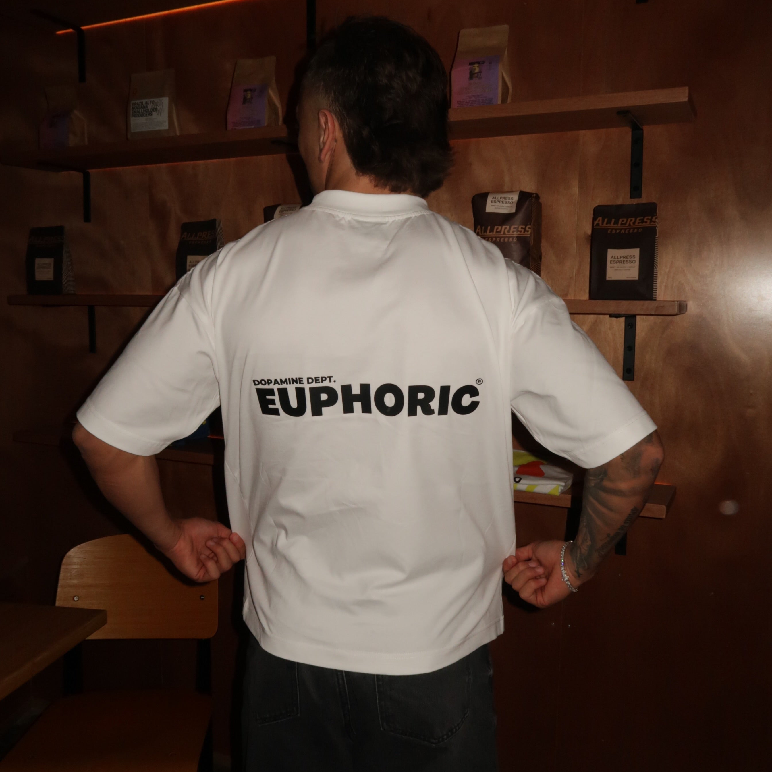Person wearing a euphoric white t-shirt showing the back logo.