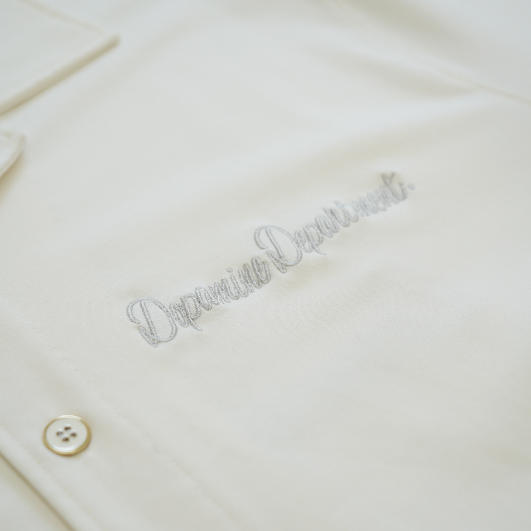 Close-up of the front logo on the euphoric pearl white button shirt