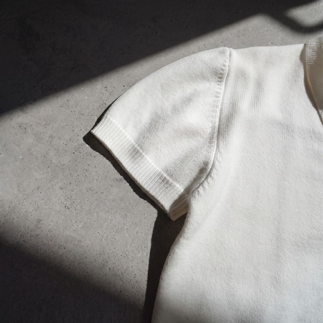 Euphoric pearl white polo shirt sleeve and ribbed cuff in natural sunlight on concrete floor