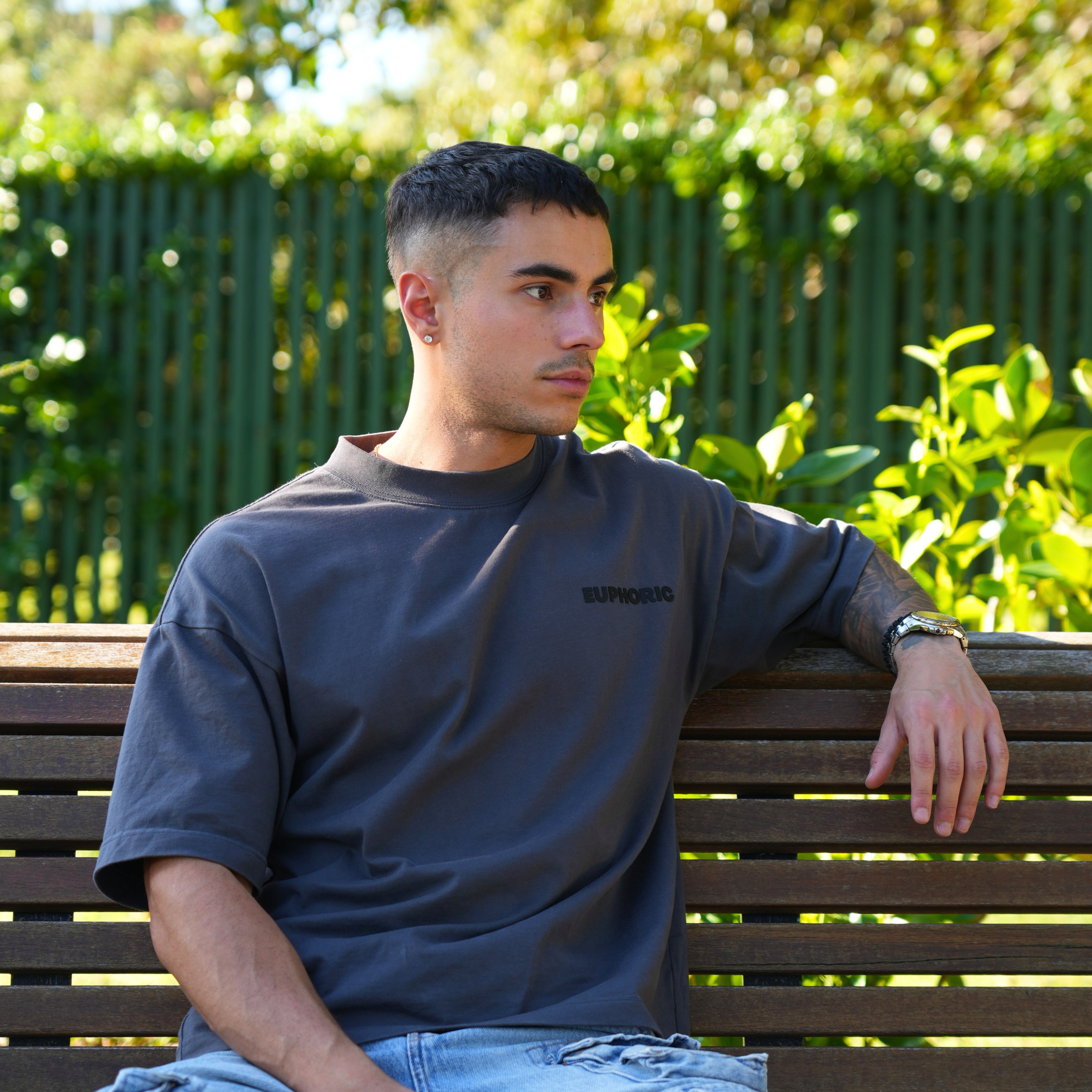 Man wearing a euphoric poppy seed t-shirt sitting on a bench outdoors