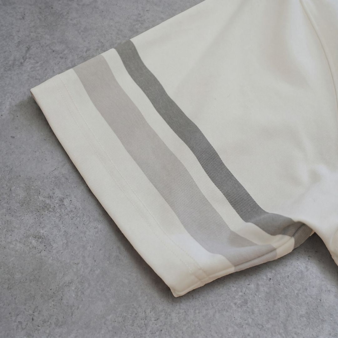 Close-up of Euphoric pearl white polo shirt sleeve showing grey and lavender stripe detailing on concrete background