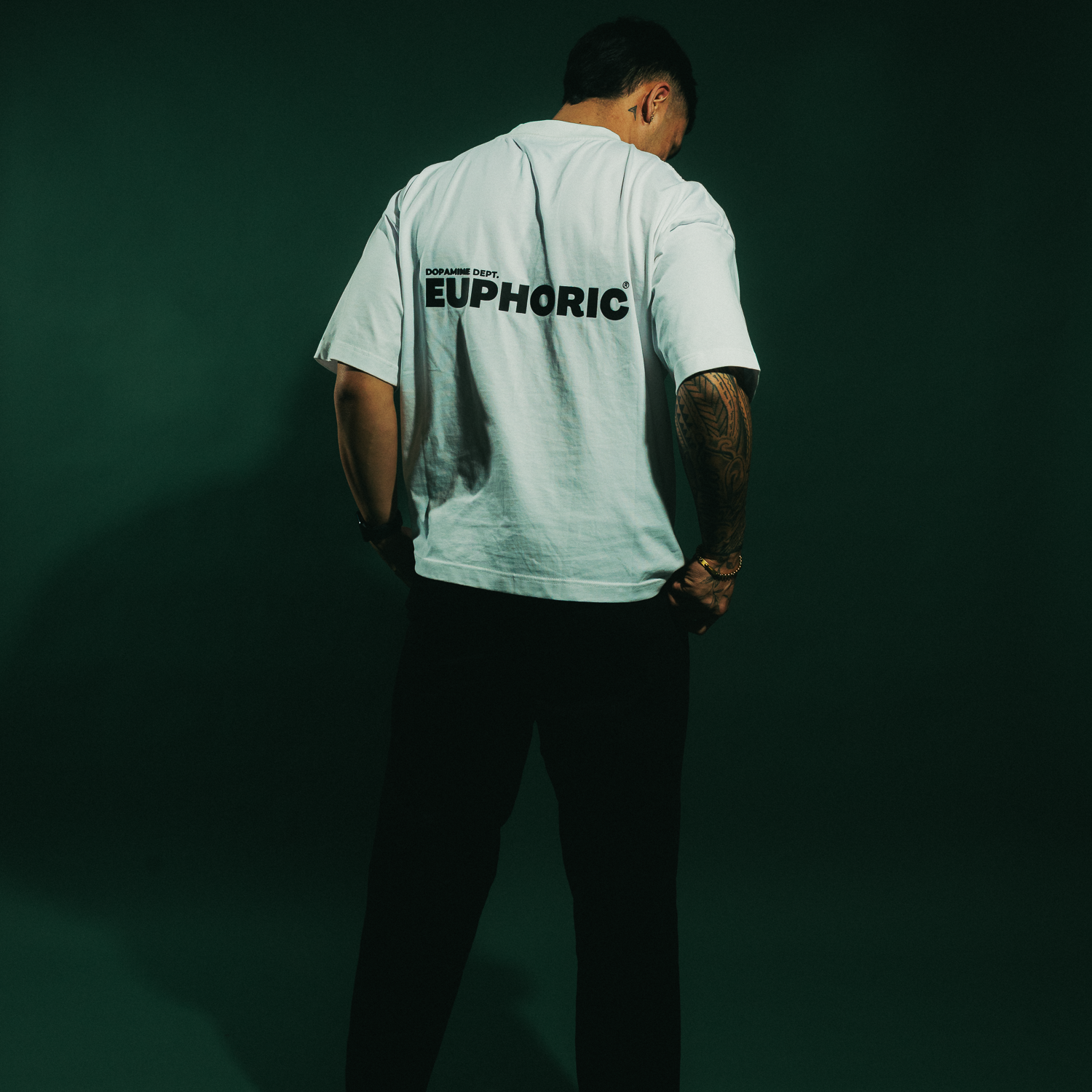 person wearing the euphoric white t-shirt showing the back logo and wearing black pants