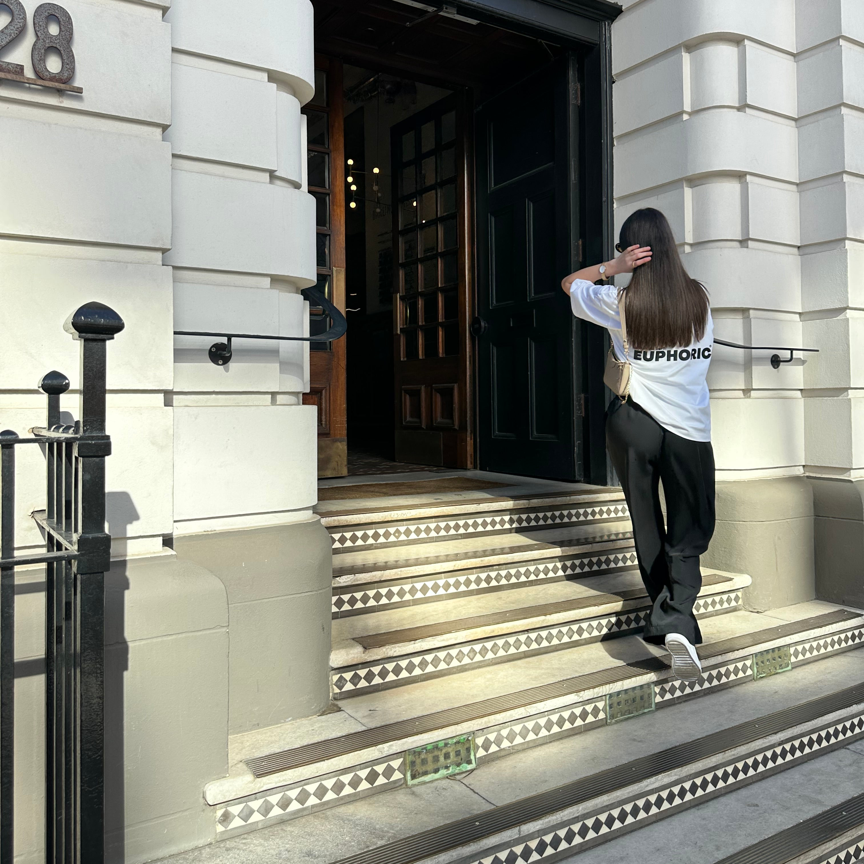 Person standing on steps outside a building wearing a white euphoric t-shirt.